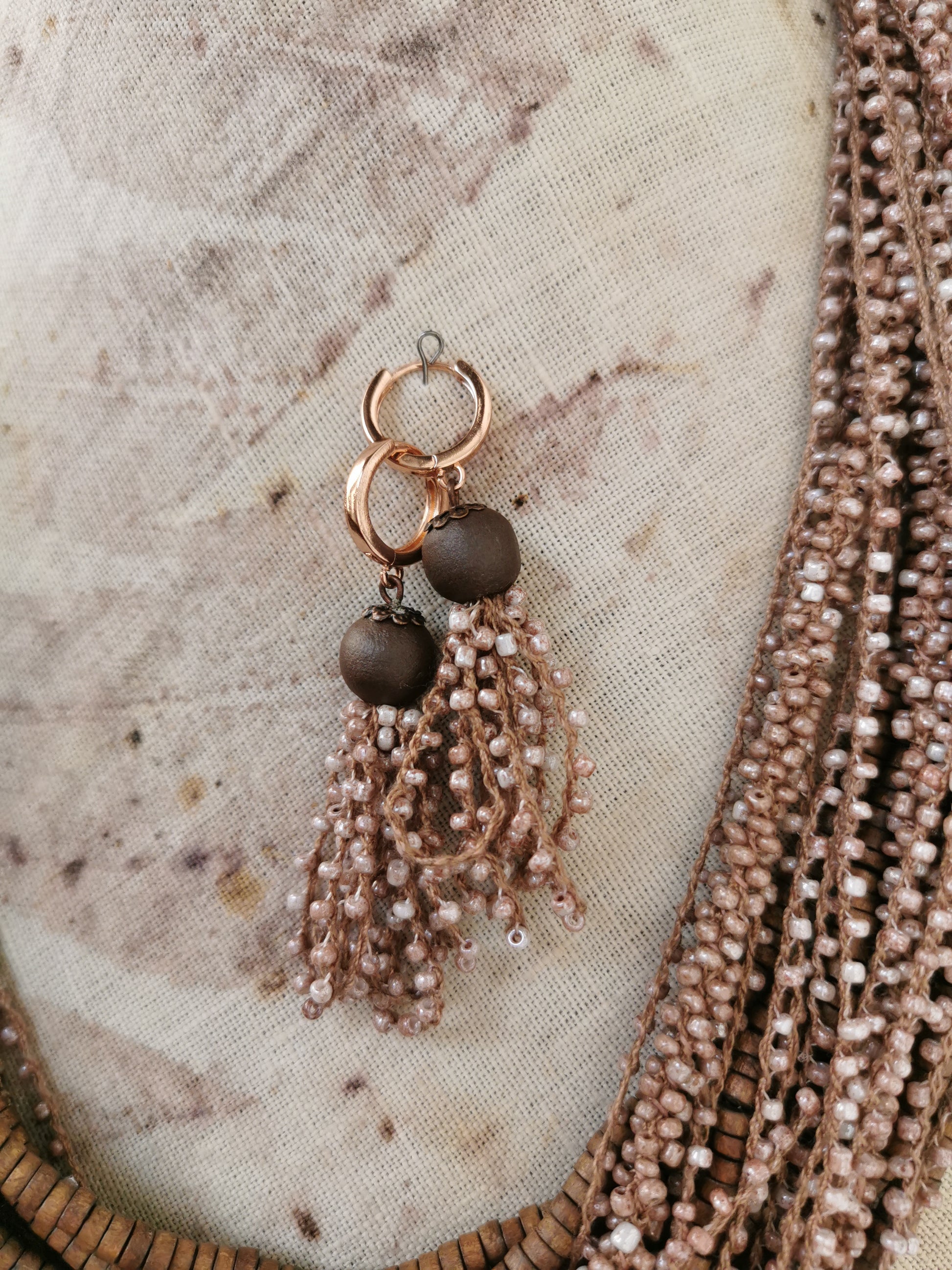 Earring with beads and tassels on a textured fabric background