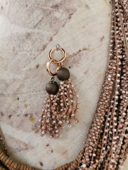 Earring with beads and tassels on a textured fabric background