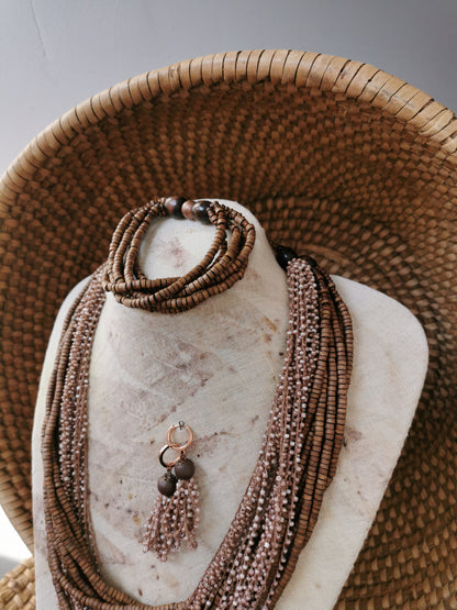 Brown beaded necklace on a mannequin bust with a woven basket in the background