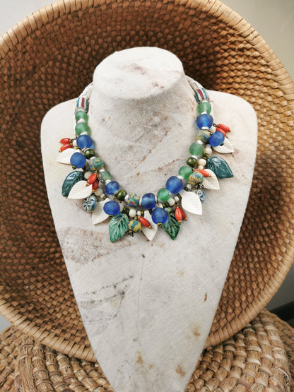 Colorful whimsical floral charm necklace  on a marble bust with a woven basket background