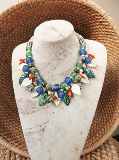 Colorful whimsical floral charm necklace on a stone bust with a woven background