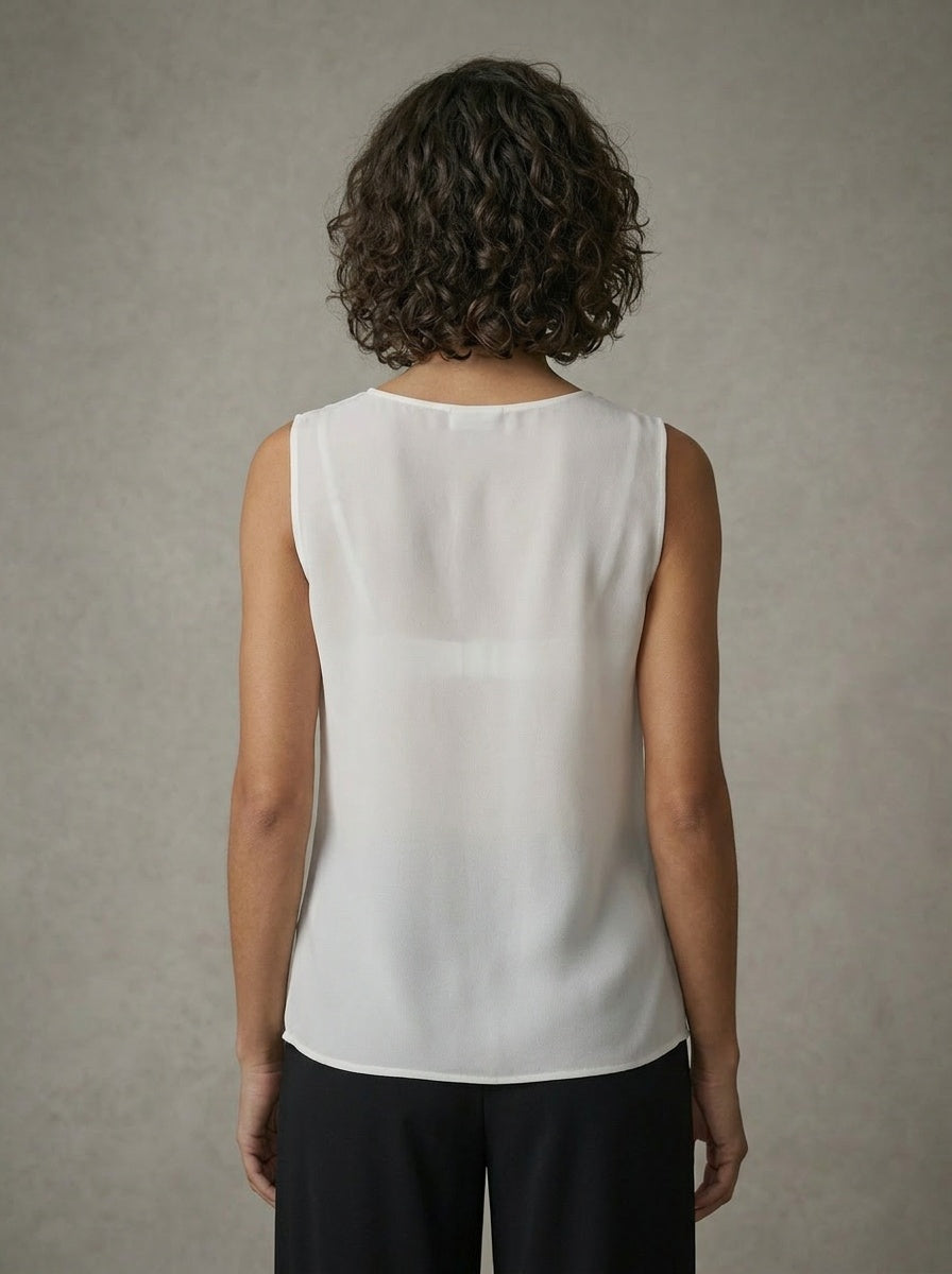 Person wearing a white sleeveless top against a neutral background
