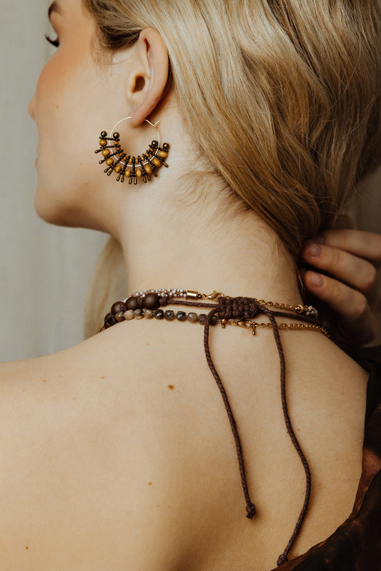 Close-up of a person wearing intricate jewelry including earrings and a necklace.